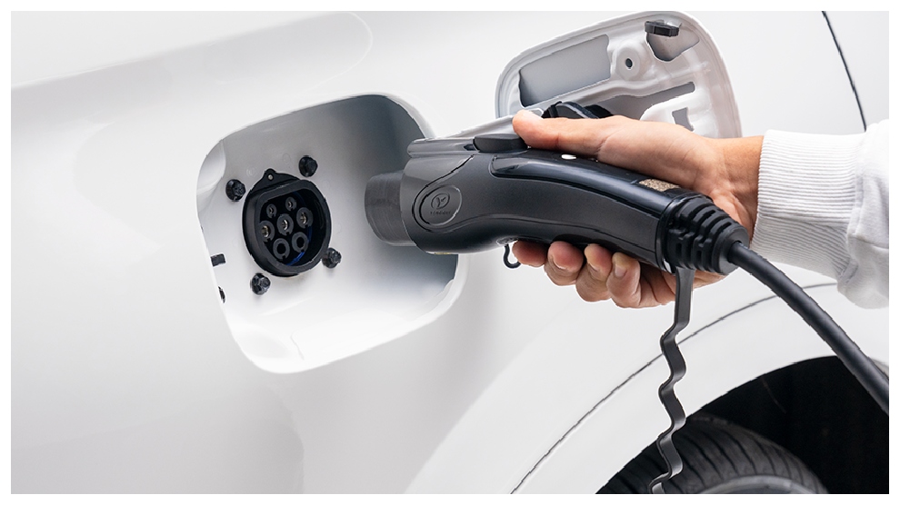 <p>Persona enchufando la SUV DFSK E5 hibrida para carga.</p>